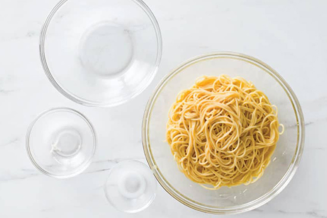 Eine Schüssel Spaghetti und eine Schüssel Pasta in einer Glasschüssel auf einem Tisch.