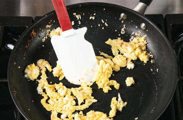 Eier in einer Pfanne mit einem Spatel kochen.