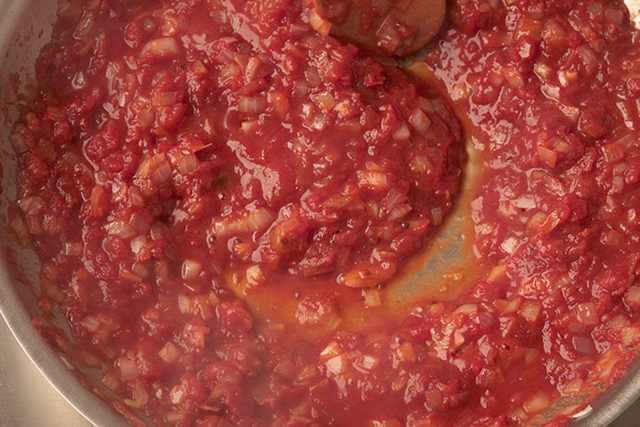 Die Sauce mit Tomatenmark und Zwiebeln andicken