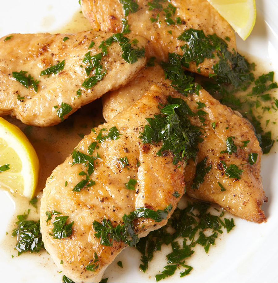 Eine Nahaufnahme eines Tellers Hähnchenschnitzel mit Pfannensauce mit einer Zitrone daneben