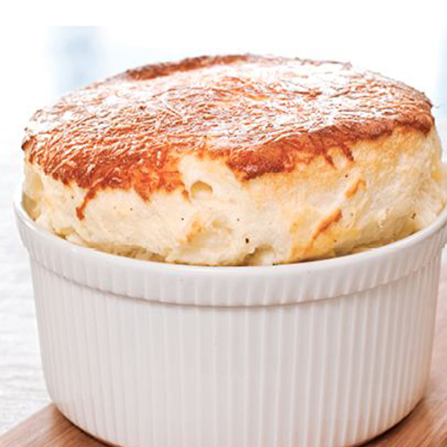 Ein weißer Teller mit einem gebackenen Kartoffelgericht, garniert mit Käse-Soufflé.