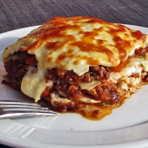 Ein Teller mit einer Portion Käse-Lasagne, die verführerisch und frisch aussieht, bereit für den Genuss.