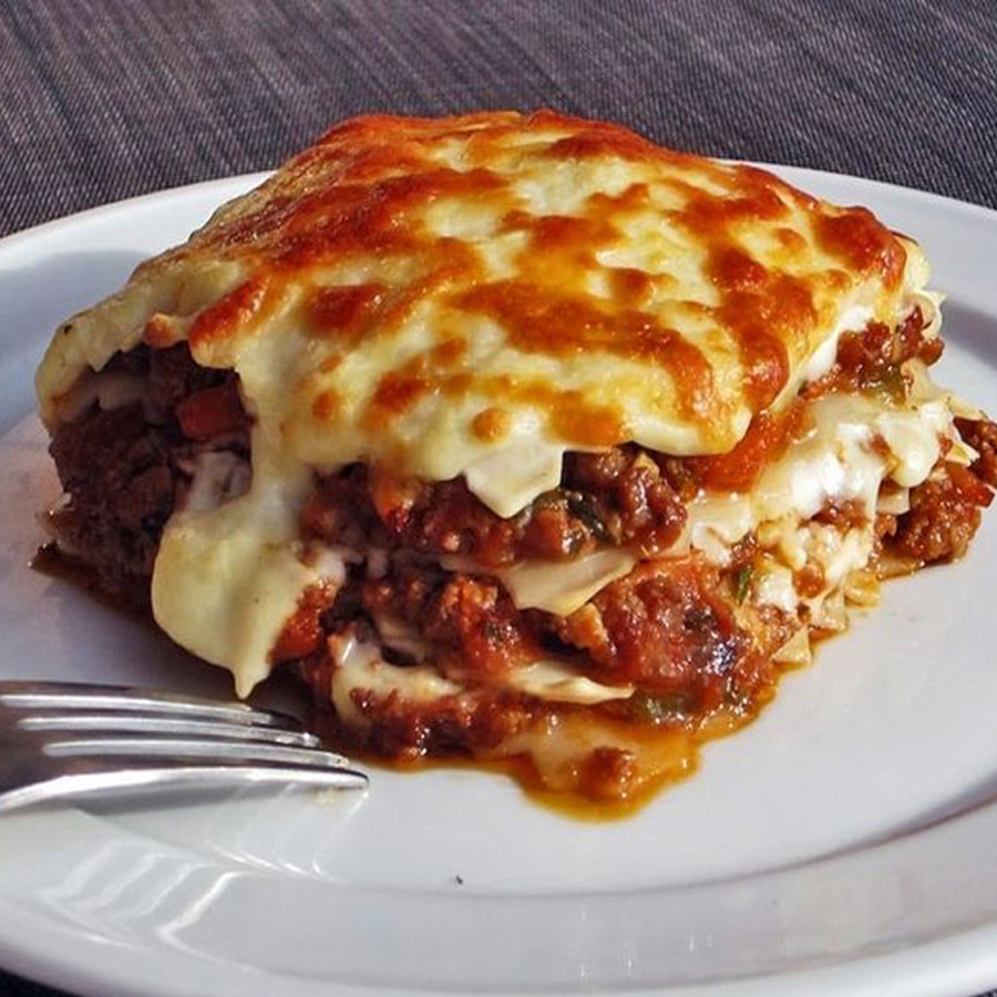 Ein Stück Käse-Lasagne auf einem weißen Teller, appetitlich angerichtet und bereit zum Genießen.