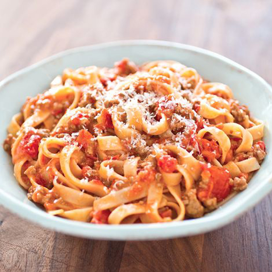 Pasta mit Bolognese-Soße, zartem Fleisch und saftigen Tomaten in einer ansprechenden Schüssel serviert.