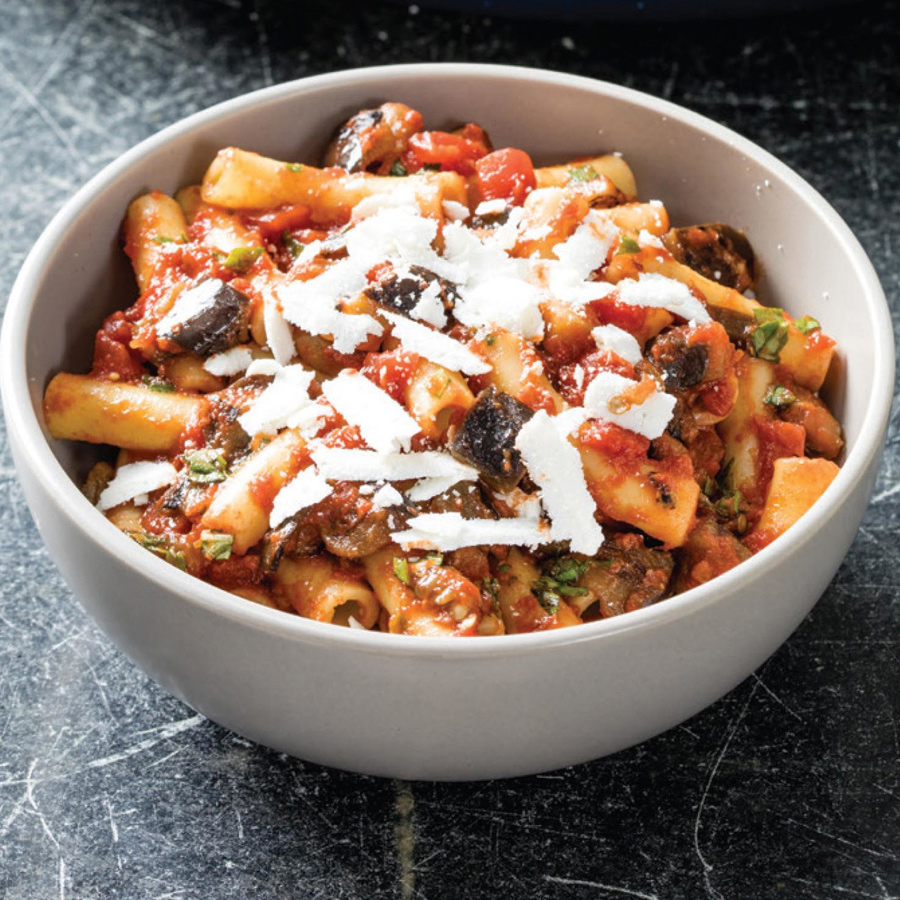 Eine Schüssel Pasta alla Norma mit Fleisch und Gemüse, eine köstliche und farbenfrohe Mahlzeit.