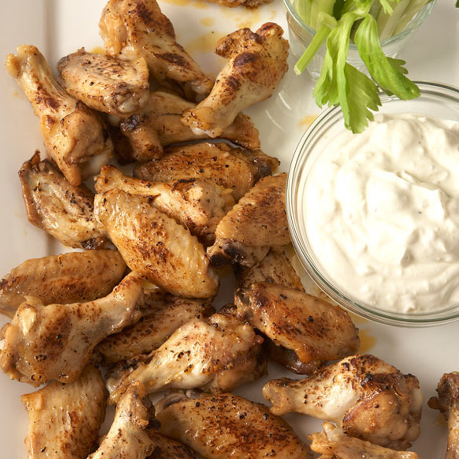 Bild eines Chicken Wings Buffalo Style Tellers mit einer Tasse Joghurt daneben. super