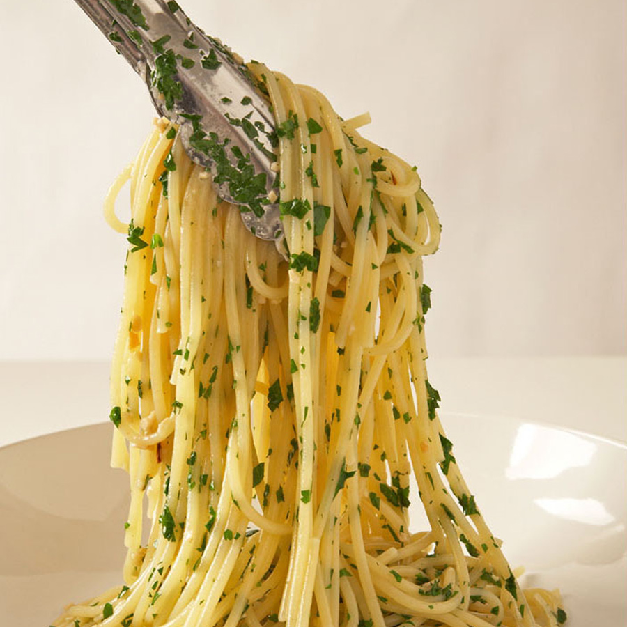 Eine Gabel hält einen Teller Spaghetti Aglio E Olio.