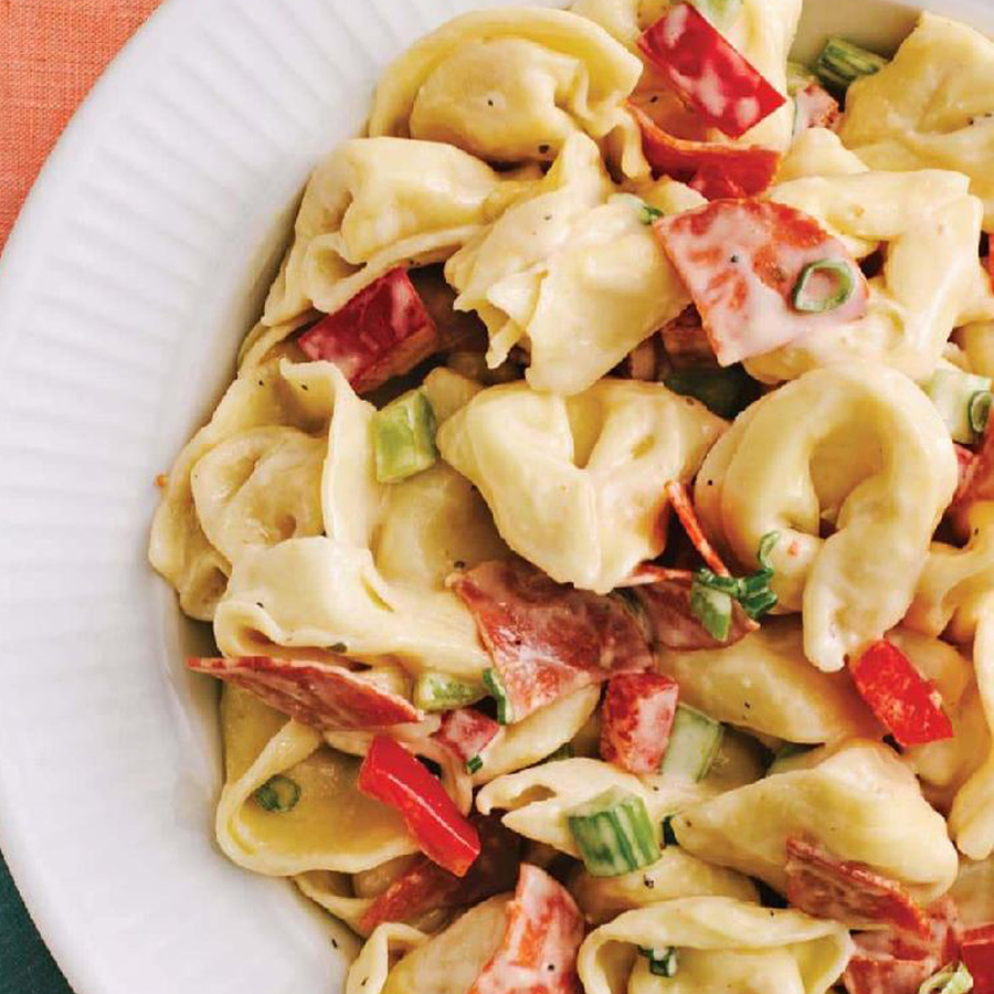 Ein Teller Weltbester Tortellini-Salat mit bunten Paprikaschoten und geschmolzenem Käse obendrauf.